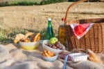 Picnic basket and different food and drinks on hay field