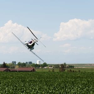 Back of a helicopter in a steep bank while turning to make another pesticide spraying run on the cornfield.
