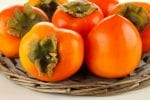 Ripe persimmons on wicker stand close up