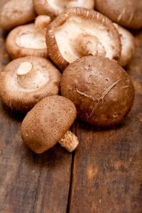 fresh shiitake mushrooms on a rustic wood table